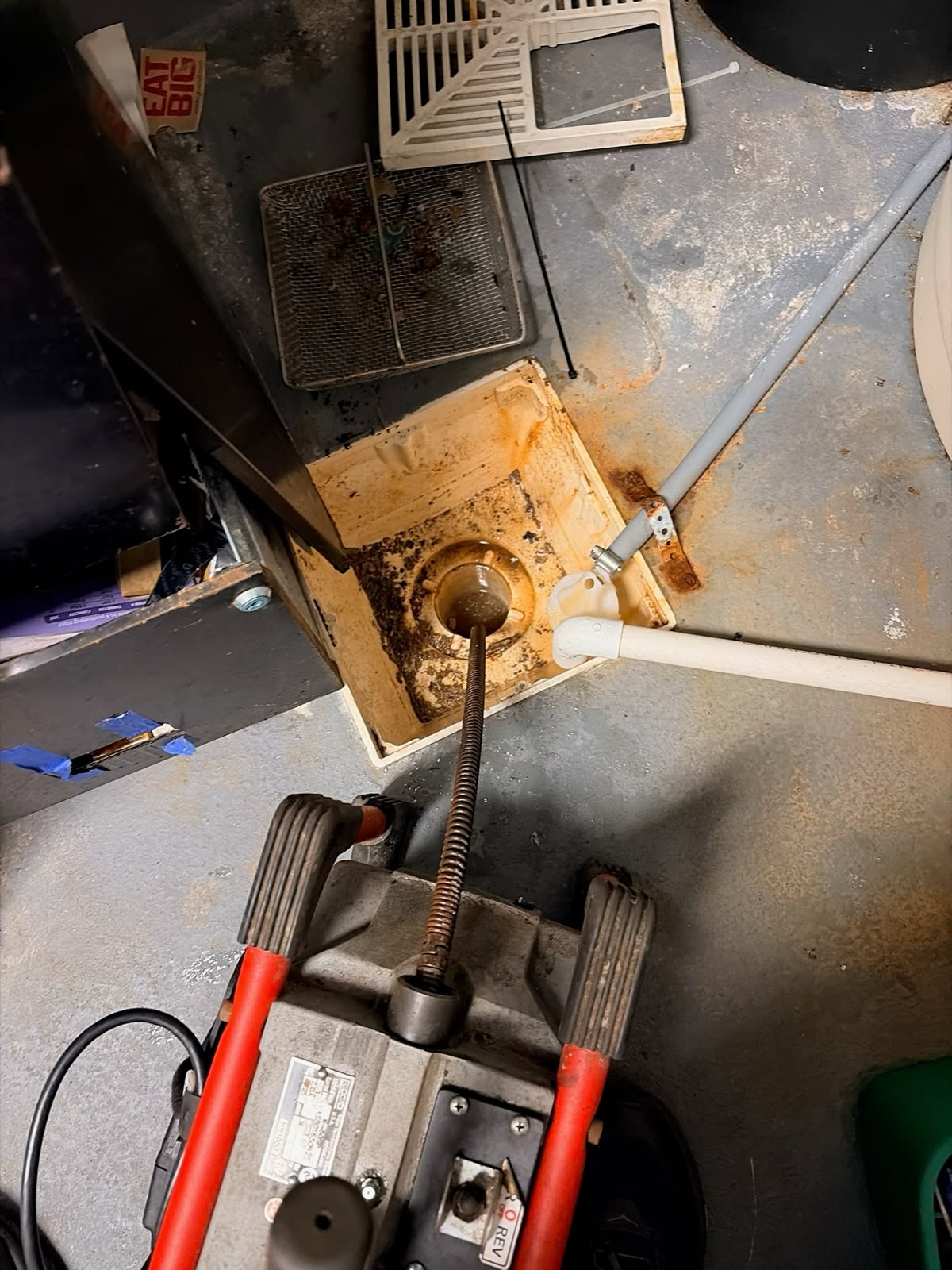 Drain cleaning machine positioned at a commercial floor drain