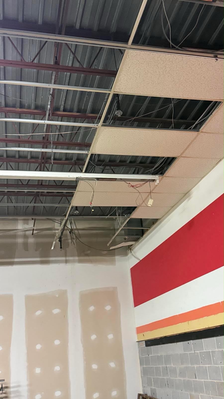 Commercial interior with exposed ceiling grid and drywall work