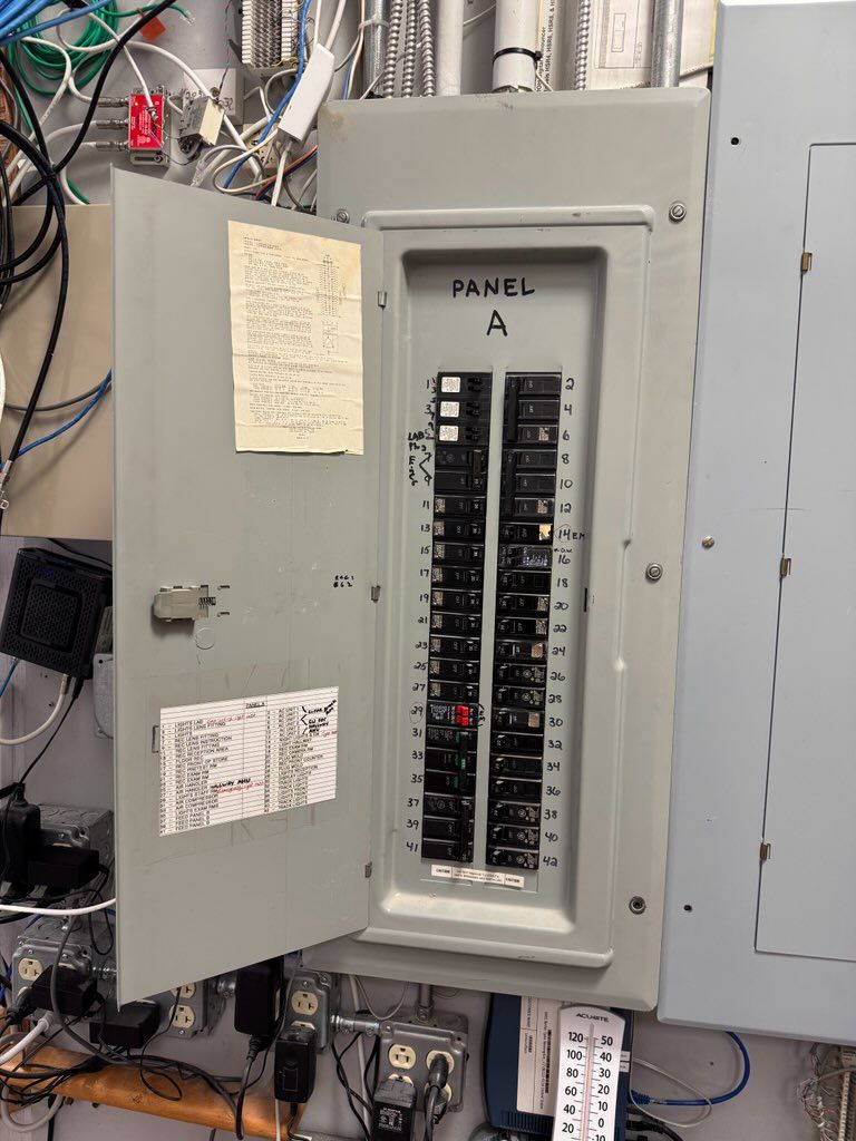 Open commercial electrical breaker panel with labeled circuits